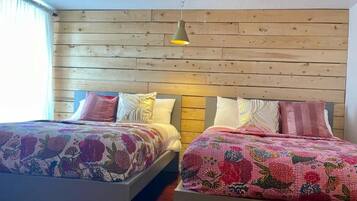 Ein Zimmer mit zwei Betten, jedes mit blumigem Bettzeug, Holzkopfteilen und einer Pendelleuchte.
