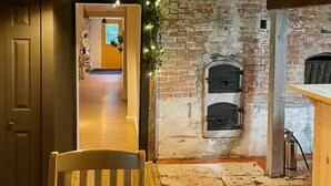 A rustic interior with exposed brick walls, a wooden chair, and a brick fireplace. - Jaune Hôtel Boutique (Saint-Gédéon)