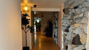 A hallway with wooden flooring, a stone wall on one side, and two pendant lights. - Jaune Hôtel Boutique (Saint-Gédéon)