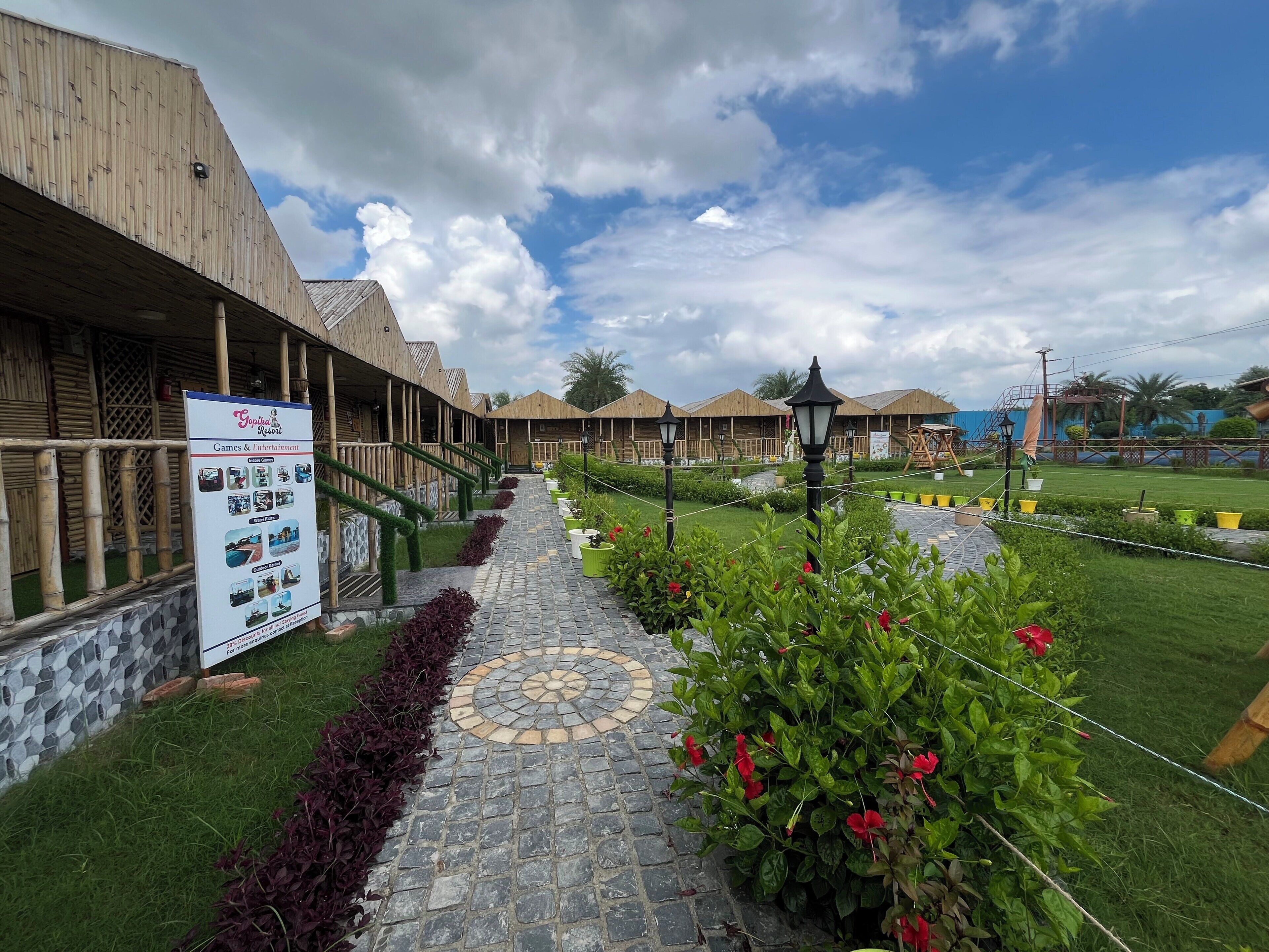 A resort with wooden buildings, a paved pathway, and a signboard.