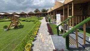 Un resort con edificios de estilo bambú, un camino pavimentado y un cartel.