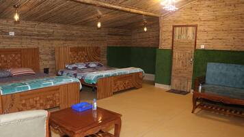 A room with two wooden beds, a sofa, a small wooden table, and a door.