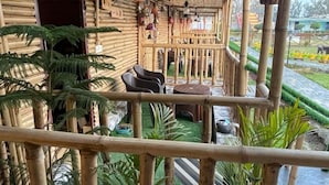 Un espacio al aire libre cubierto con estructuras de bambú, plantas en macetas y asientos exteriores.