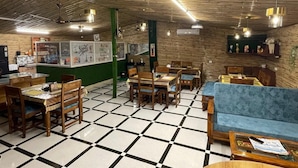 Un restaurante con suelo de cuadros, muebles de madera y una pared de acento verde.