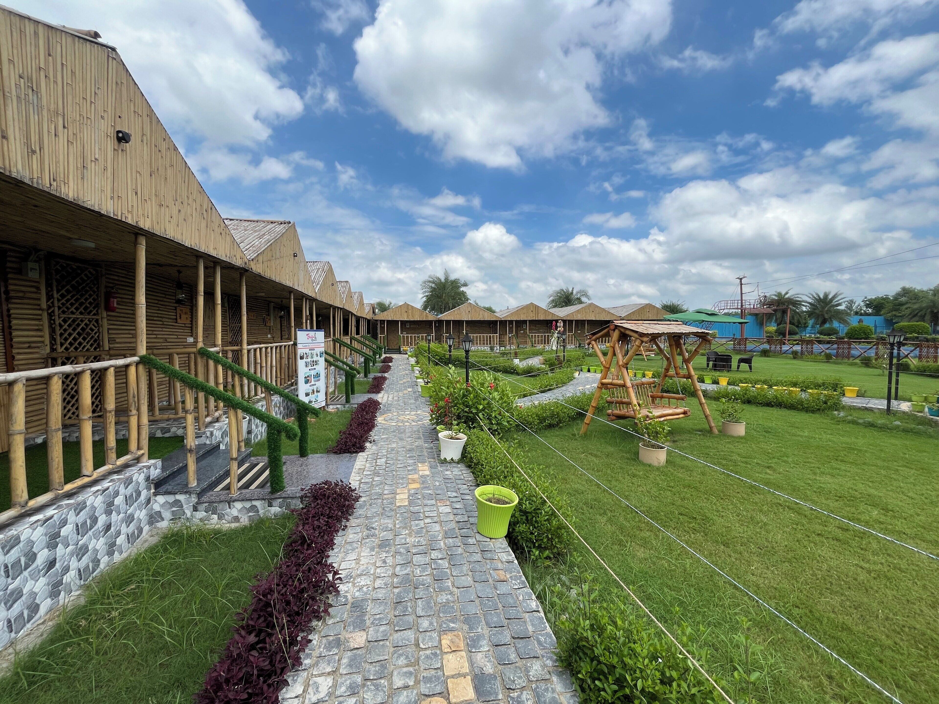 A row of wooden buildings with a stone pathway leading to a garden area.