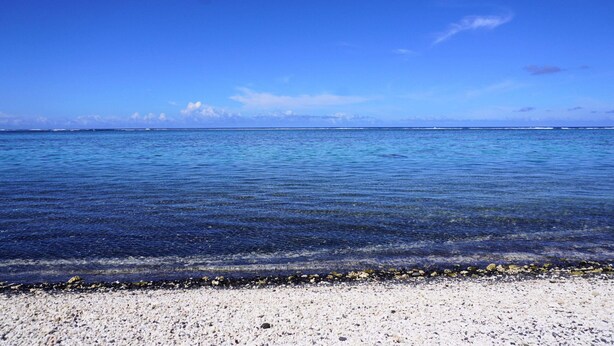 Una spiaggia con acqua cristallina, un litorale di ciottoli e un orizzonte lontano.