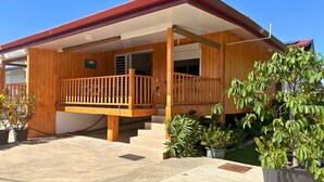 Una casa in legno con un balcone, una scala e piante in vaso.