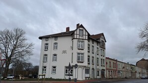 A multi-story building with a traditional architectural style, featuring a prominent corner entrance and a visible year marking on the facade. - Modernes Apartment in Minden am Hauptbahnhof (Minden)