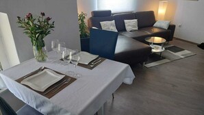 A dining area with a table set for two, a sofa, and a lamp. - Modernes Apartment in Minden am Hauptbahnhof (Minden)