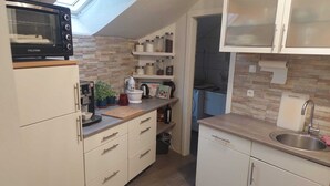 A compact kitchen with a skylight, white cabinets, a microwave, and a sink. - Modernes Apartment in Minden am Hauptbahnhof (Minden)