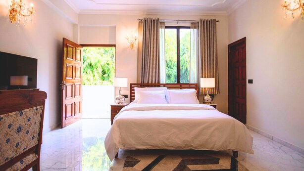 A hotel room with a large bed, two bedside tables with lamps, a wooden chair, and a TV.