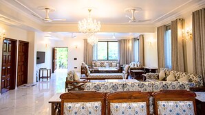 A spacious living room with a chandelier, sofas, and a television.