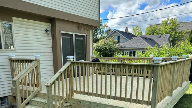 Una terraza de madera con una escalera que lleva a una casa.