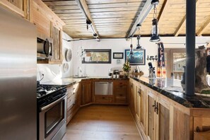 Una cocina con armarios de madera, electrodomésticos de acero inoxidable y techo de madera.