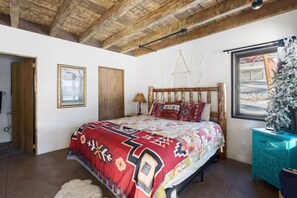 A bedroom with a wooden bed, a window with a view, and a small Christmas tree. - The Dream Catcher| Modern Rustic w/ Hot Tub (Big Bear Lake)