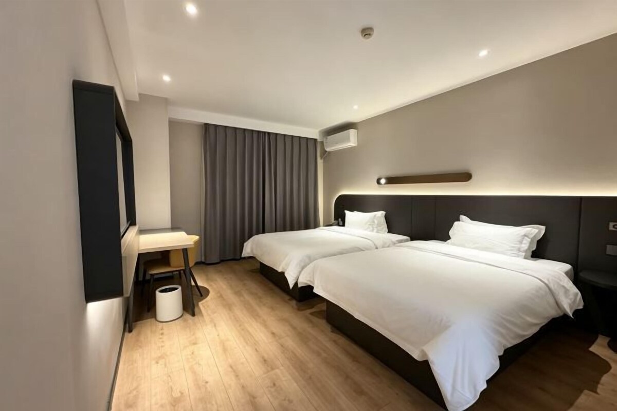 Une chambre d’hôtel avec deux lits, un bureau, une chaise et une poubelle.