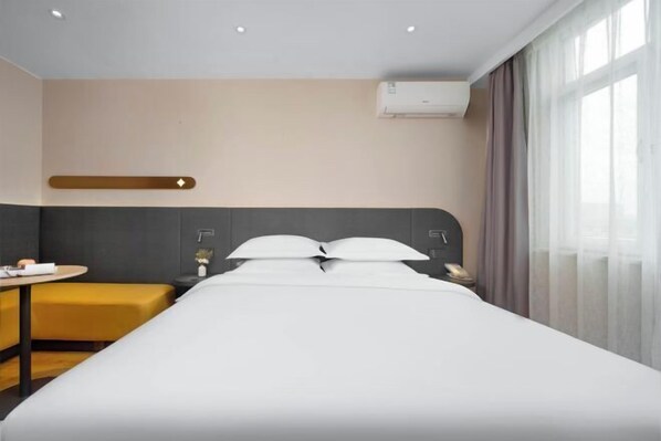 A modern hotel room with a large bed, a bedside table, a small table, and a sofa. - Jinjiang Inn Hotel (Zhengzhou Ocean Park Wenhua Road Branch) (Zhengzhou)