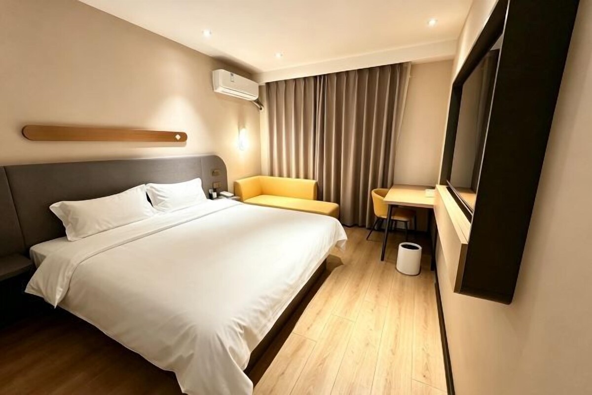 Une chambre d’hôtel avec un lit, un bureau, une chaise et un miroir.