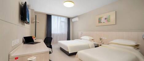 A hotel room with two beds, a desk with a laptop, a chair, and a TV mounted on the wall.