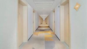 A hotel corridor with a patterned carpet, white walls, and doors on both sides. - Jinjiang Inn Hotel (Zhengzhou Ocean Park Wenhua Road Branch) (Zhengzhou)