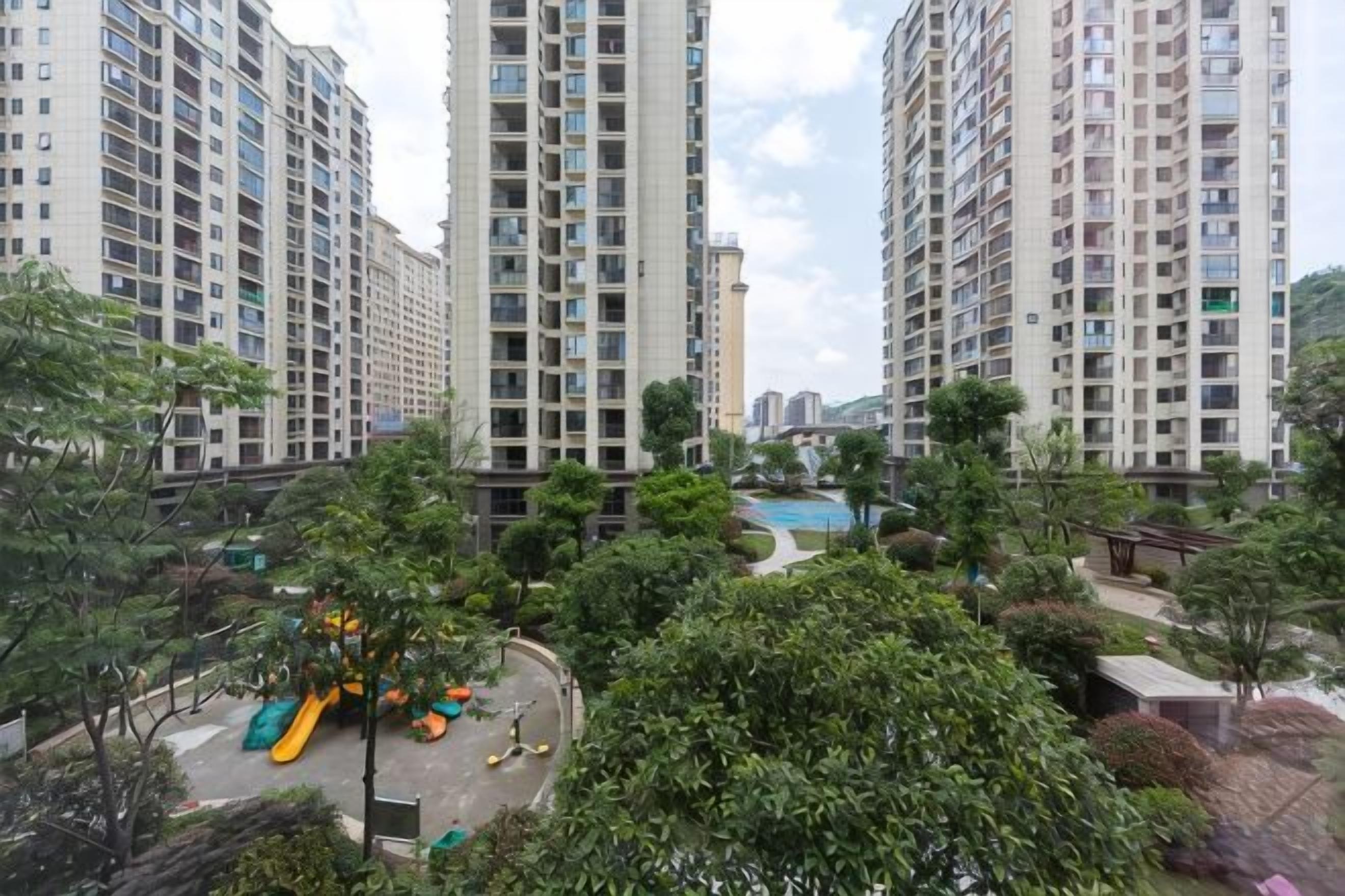 Zona residencial amb edificis d'apartaments alts, un parc infantil i una piscina.