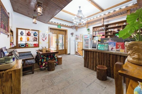 A rustic interior with wooden beams, a chandelier, and a variety of pottery displayed on shelves.