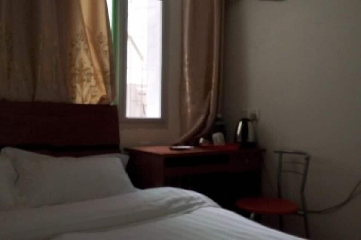 A hotel room with a bed, a desk, a chair, and a window with curtains.