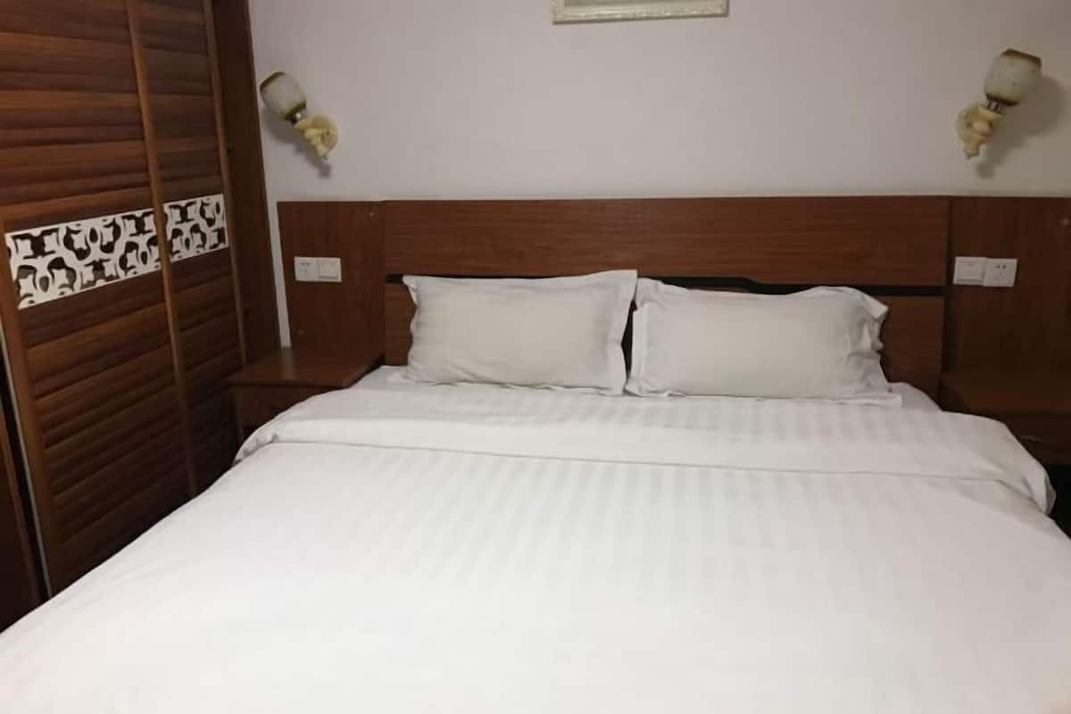 A neatly made bed with white linens, a wooden headboard, and two wall-mounted lamps.