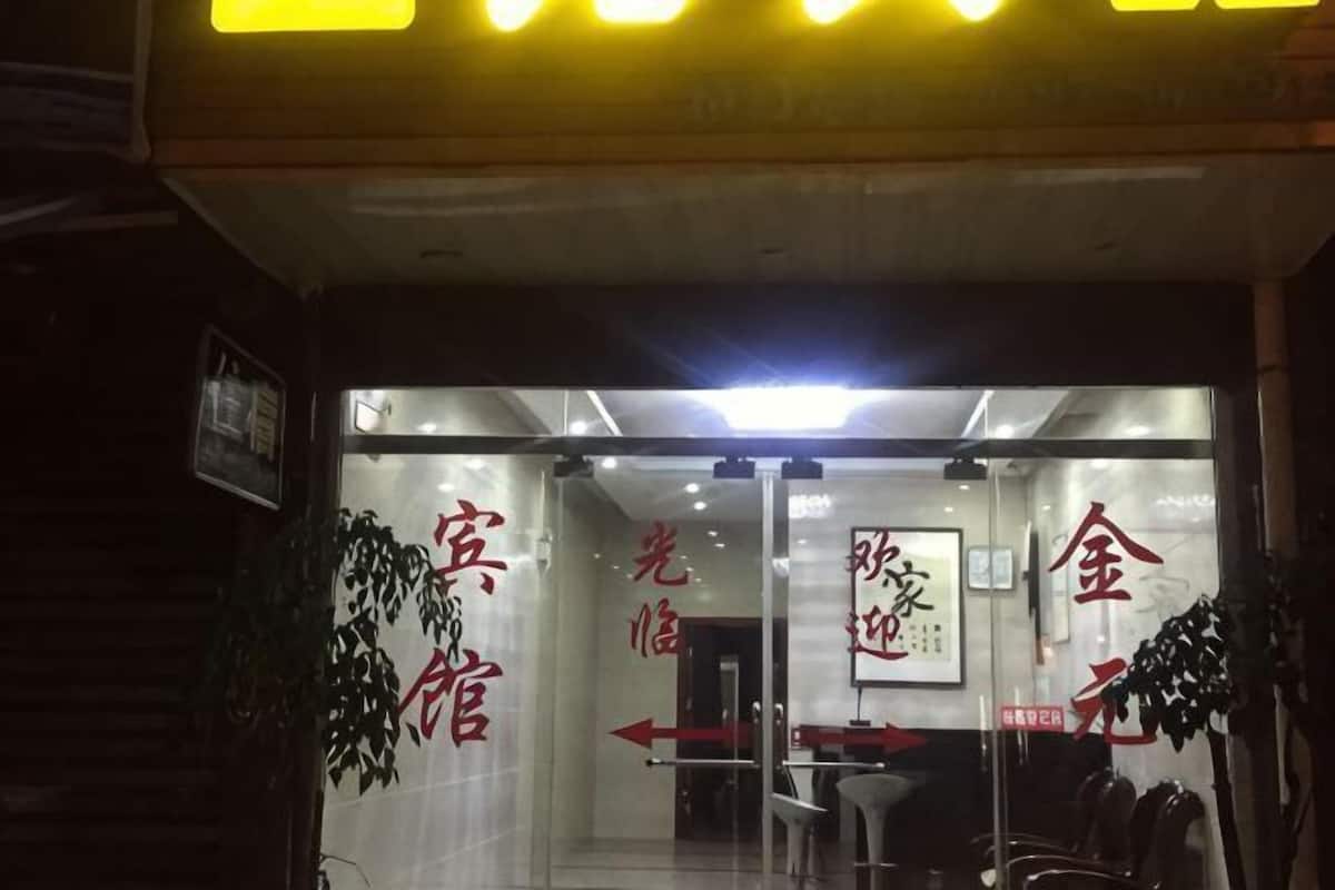 A hotel entrance with glass doors, directional signs, and a seating area inside.
