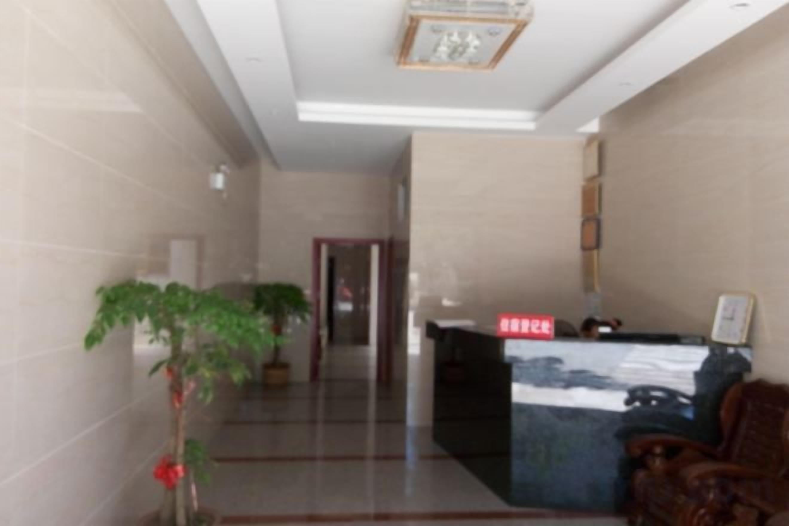 A reception area with a reception desk, a potted plant, and a door in the background.