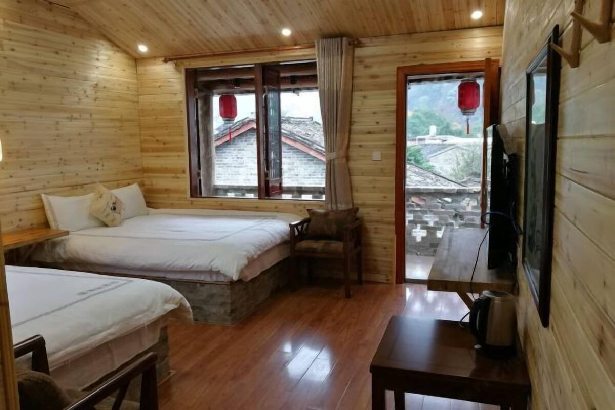 A wooden room with two beds, a table, and a TV.
