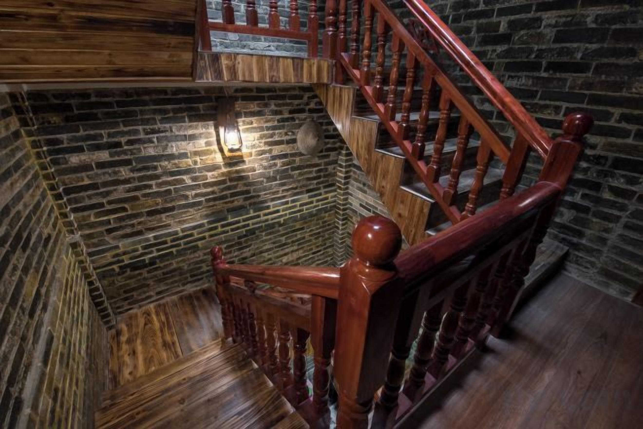 A wooden staircase with a handrail and a light fixture on the wall.