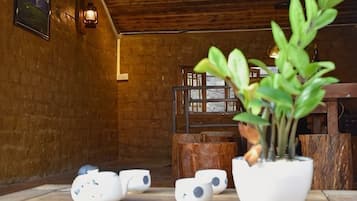 A rustic interior with wooden walls, a potted plant, and a table with white ceramic cups.