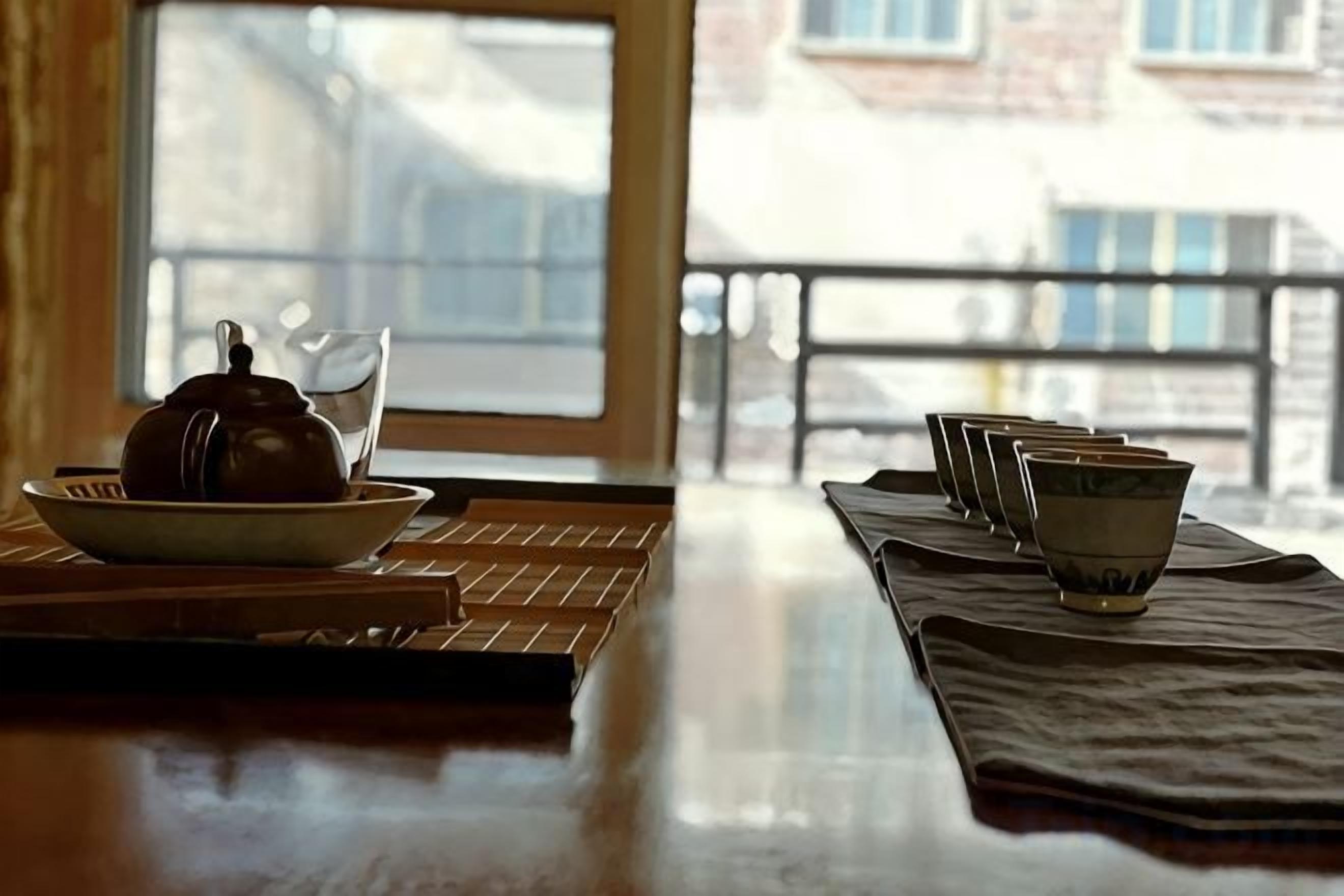 A table with a teapot and cups, a window with a view, and a balcony railing.