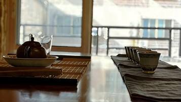 A table with a teapot and cups, a window with a view, and a balcony railing.