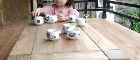 A child sitting at a wooden table with several ceramic cups.