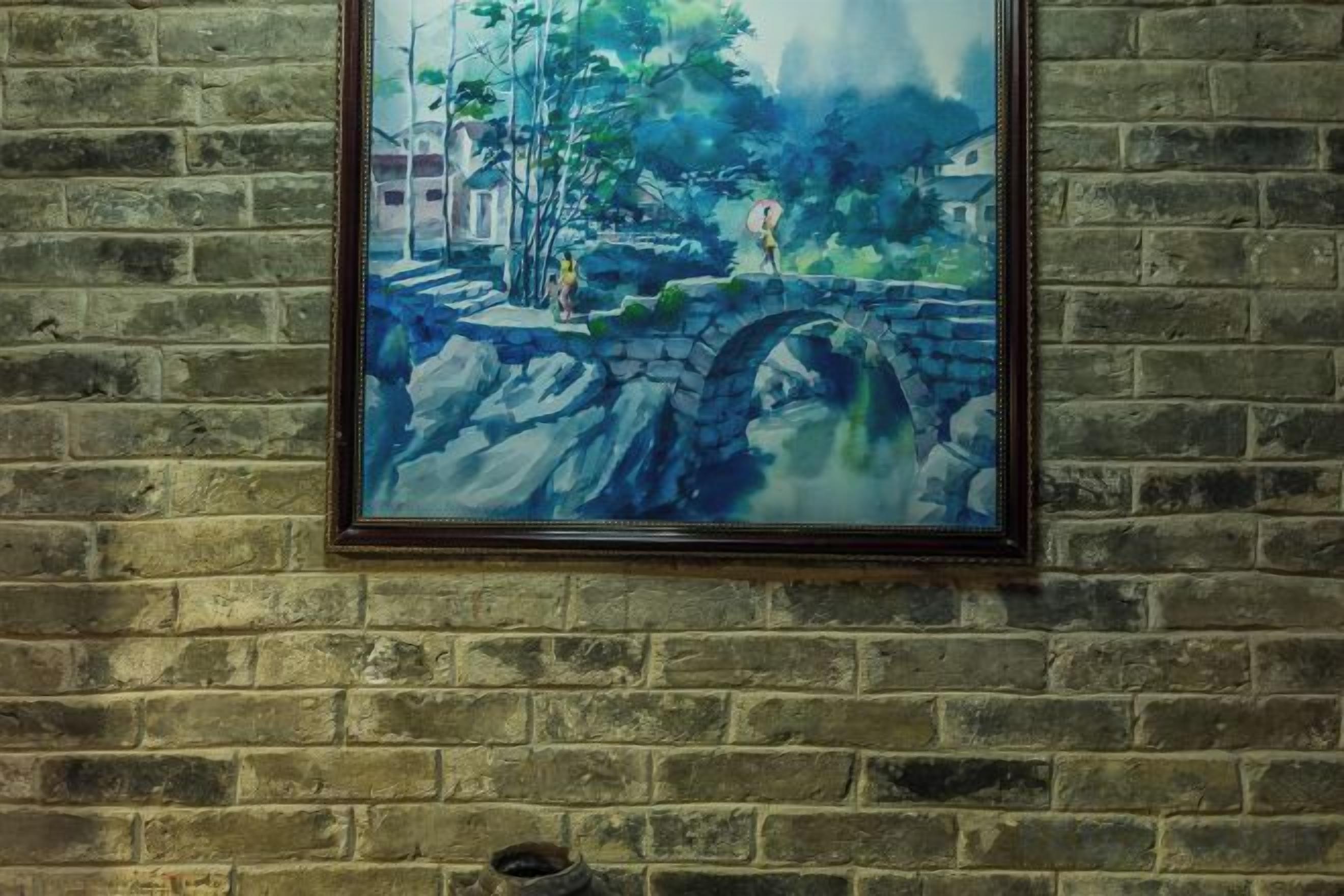 A framed painting of a bridge over a river with buildings in the background.