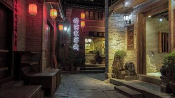 A traditional courtyard with stone steps leading to a wooden door, lanterns, and a sign indicating a restaurant.
