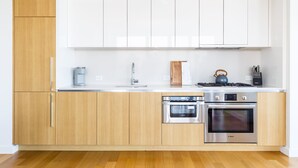 Une cuisine moderne avec des meubles en bois, des appareils en acier inoxydable et un plan de travail blanc.