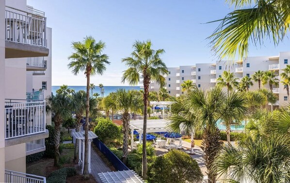 A hotel with multiple floors, outdoor seating areas, and palm trees.