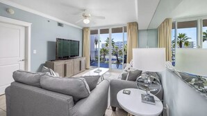 Una habitación de hotel moderna con balcón, sofá, televisor y lámpara.