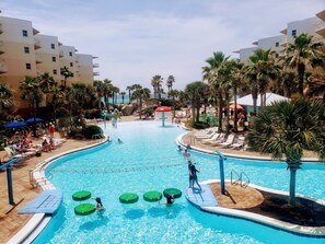 A large indoor swimming pool with multiple lanes, surrounded by palm trees and lounge chairs.