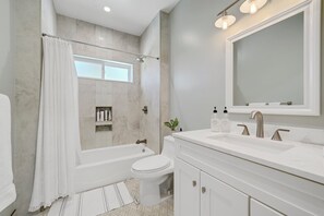 Features a large mirror above the sink and a shower area with a glass door.