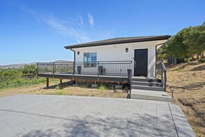 Enter through the black door and step up to a balcony with a railing.