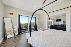 Relax in a spacious room with a large bed, full-length mirror, and a balcony offering views of the surrounding landscape.