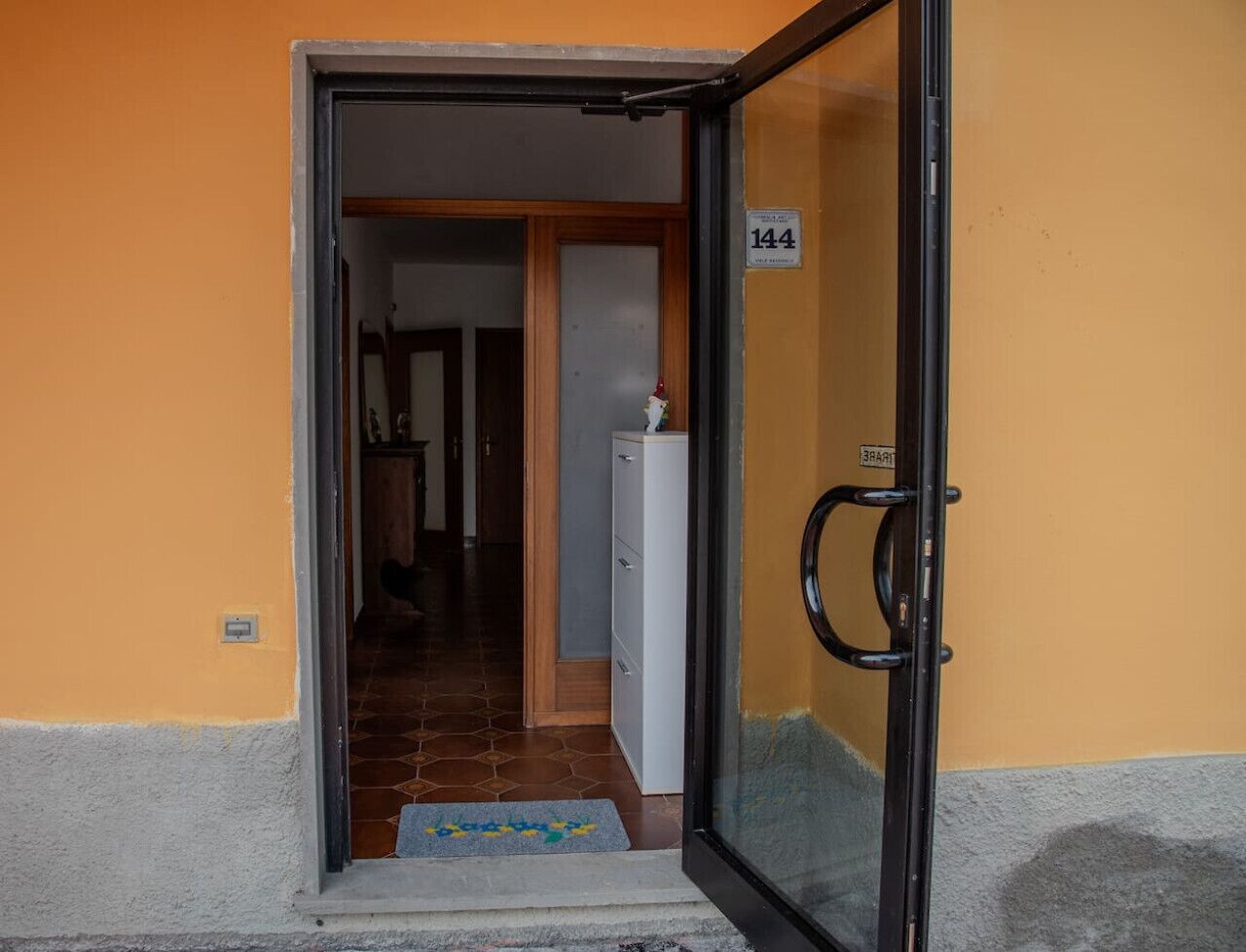 A doorway leading to a hallway with a tiled floor and a white cabinet.