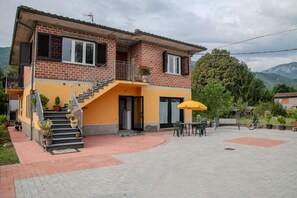 A two-story house with a brick facade, a balcony, and a staircase leading to the upper floor. - Home Mate - River Side, Rural Fun (Piano di Coreglia)