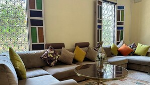 A living room with a sofa, cushions, a glass coffee table, and a patterned rug.