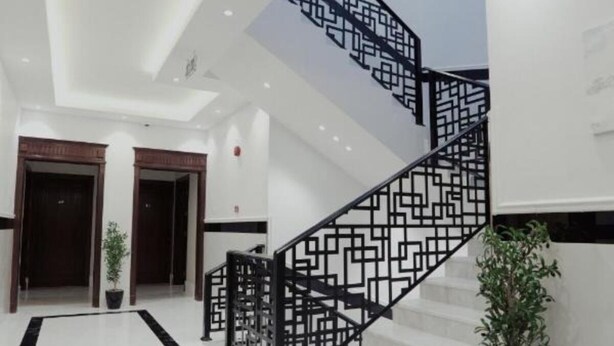 A modern interior with a white marble floor, a black geometric staircase, and wooden doors. - Nma'a Residences (Riyadh)