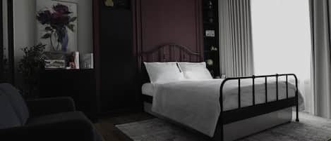 A modern bedroom with a bed, a bedside table, a chair, a bookshelf, and a large window with curtains.